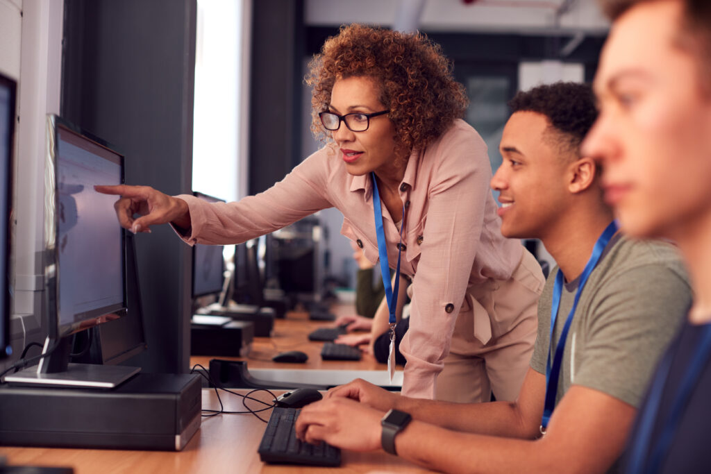 Instructor indicating something on a computer screen to a college student