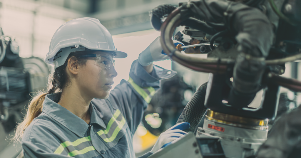 Woman in a hard hat tinkering with advanced technology manufacturing
