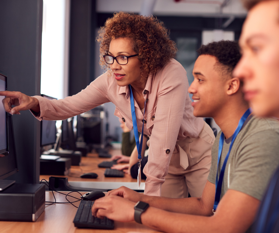 Instructor indicating something on a computer screen to a college student