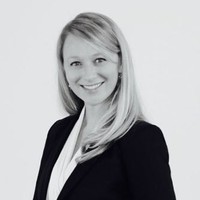 Professional black and white headshot of Alex West in a blazer, smiling at the camera
