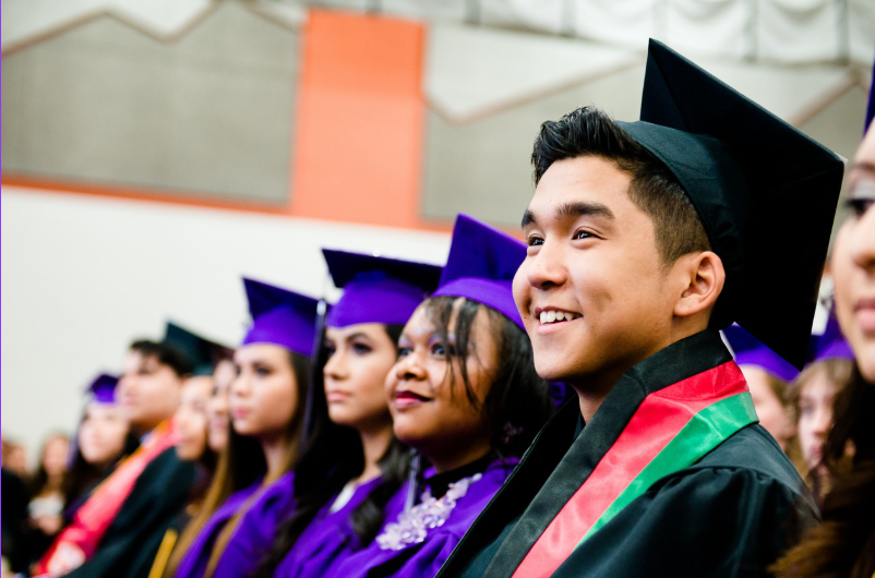 Smiling graduates seated in caps and gowns during a commencement ceremony