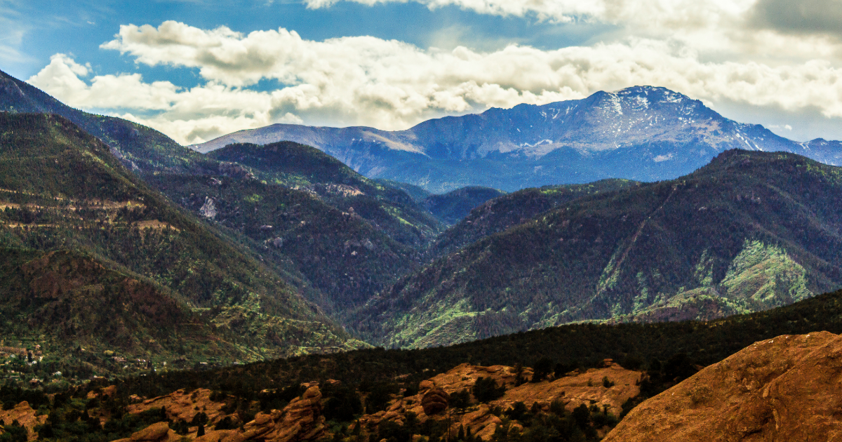 Scenic view of Colorado's Front Range with layered green foothills and snow-dusted Pikes Peak in the background